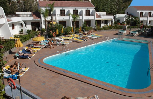 Een buitenzwembad, parasols bij het zwembad en ligstoelen