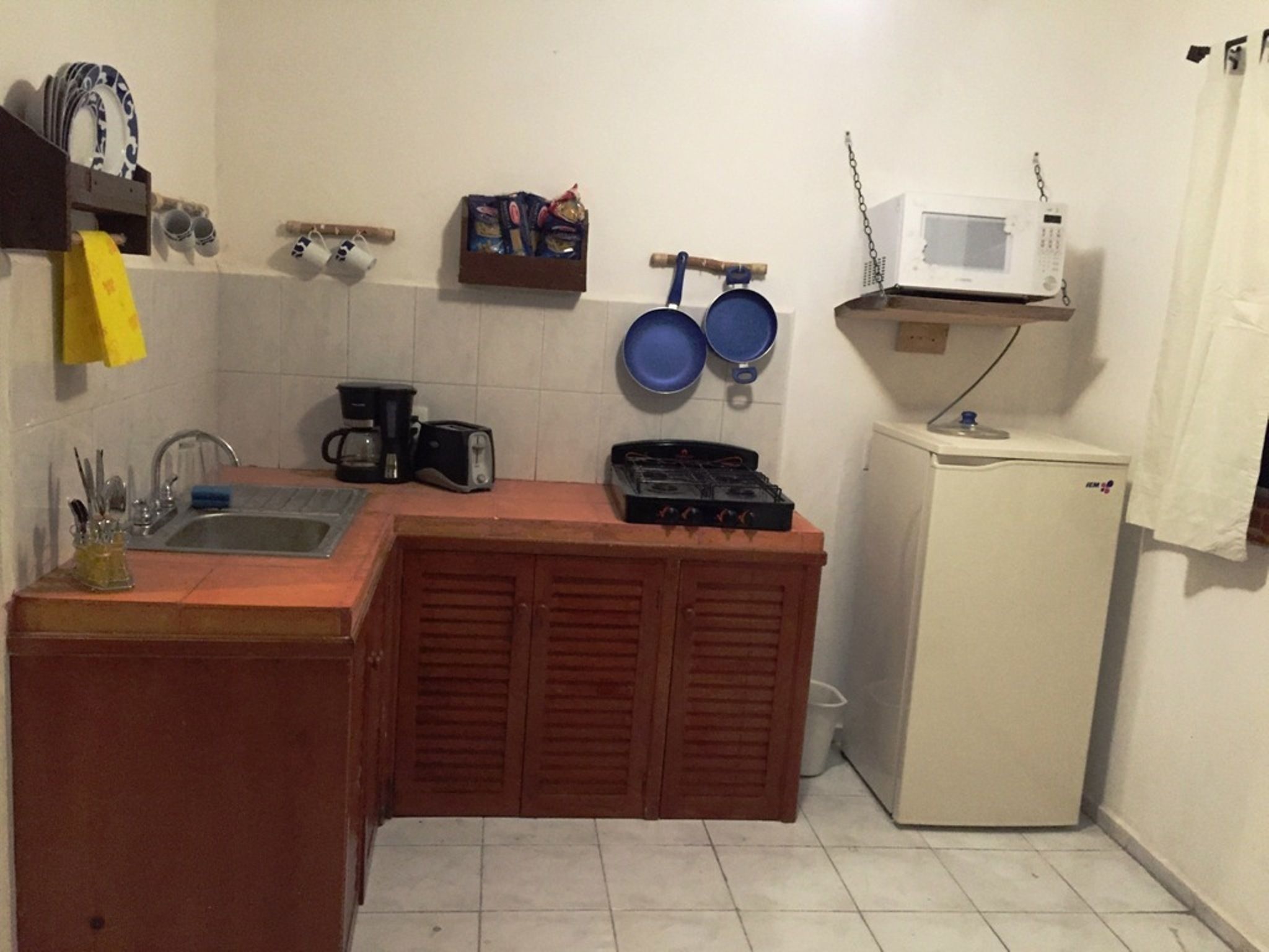 A compact kitchen with a sink, a coffee maker, a toaster, a gas stove, and a microwave.