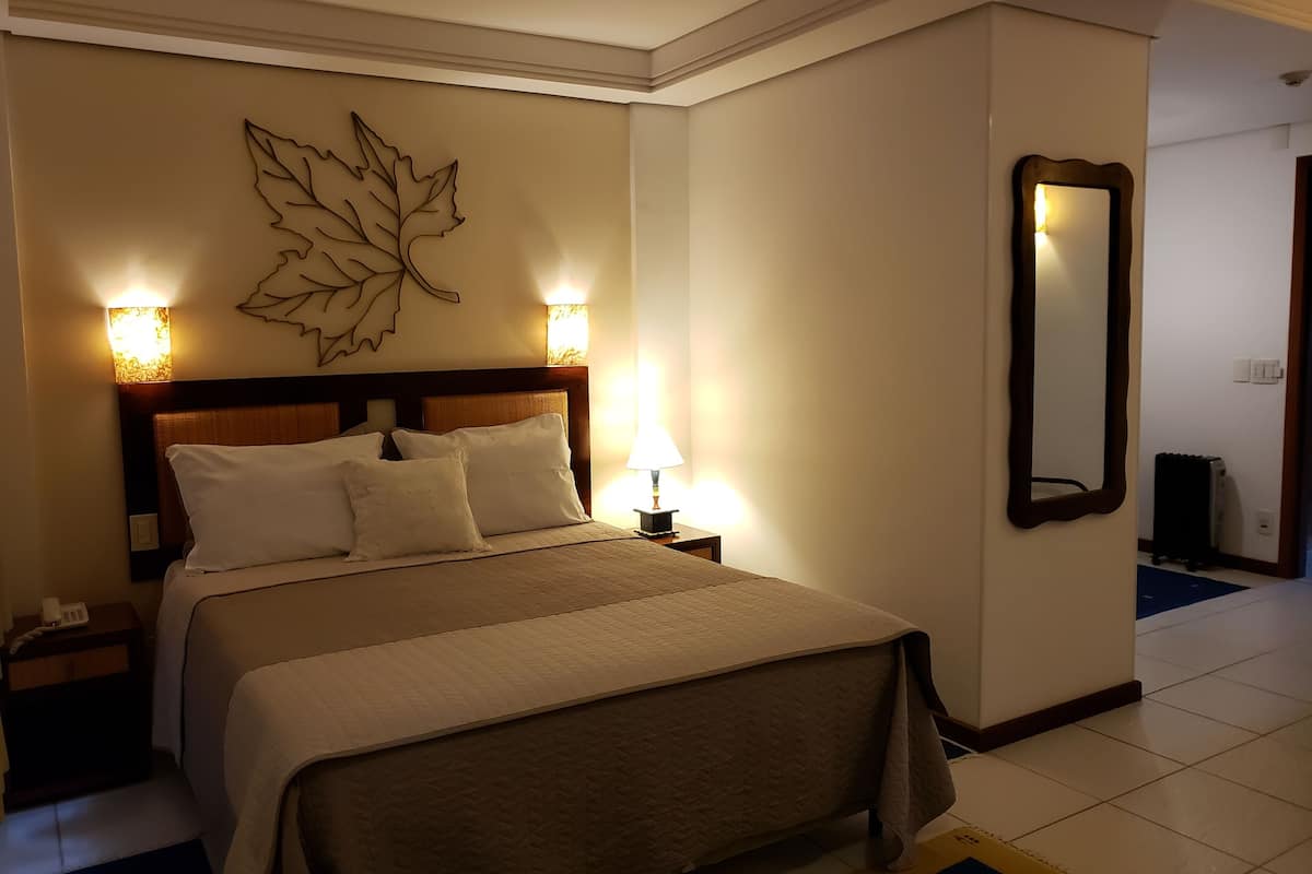 Une chambre d’hôtel avec un grand lit, deux lampes de chevet, une décoration murale en forme de feuille et un miroir.
