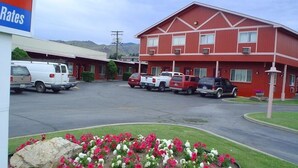Ein Motel mit roter Fassade, mehreren Parkplätzen und einem Blumenbeet im Vordergrund.