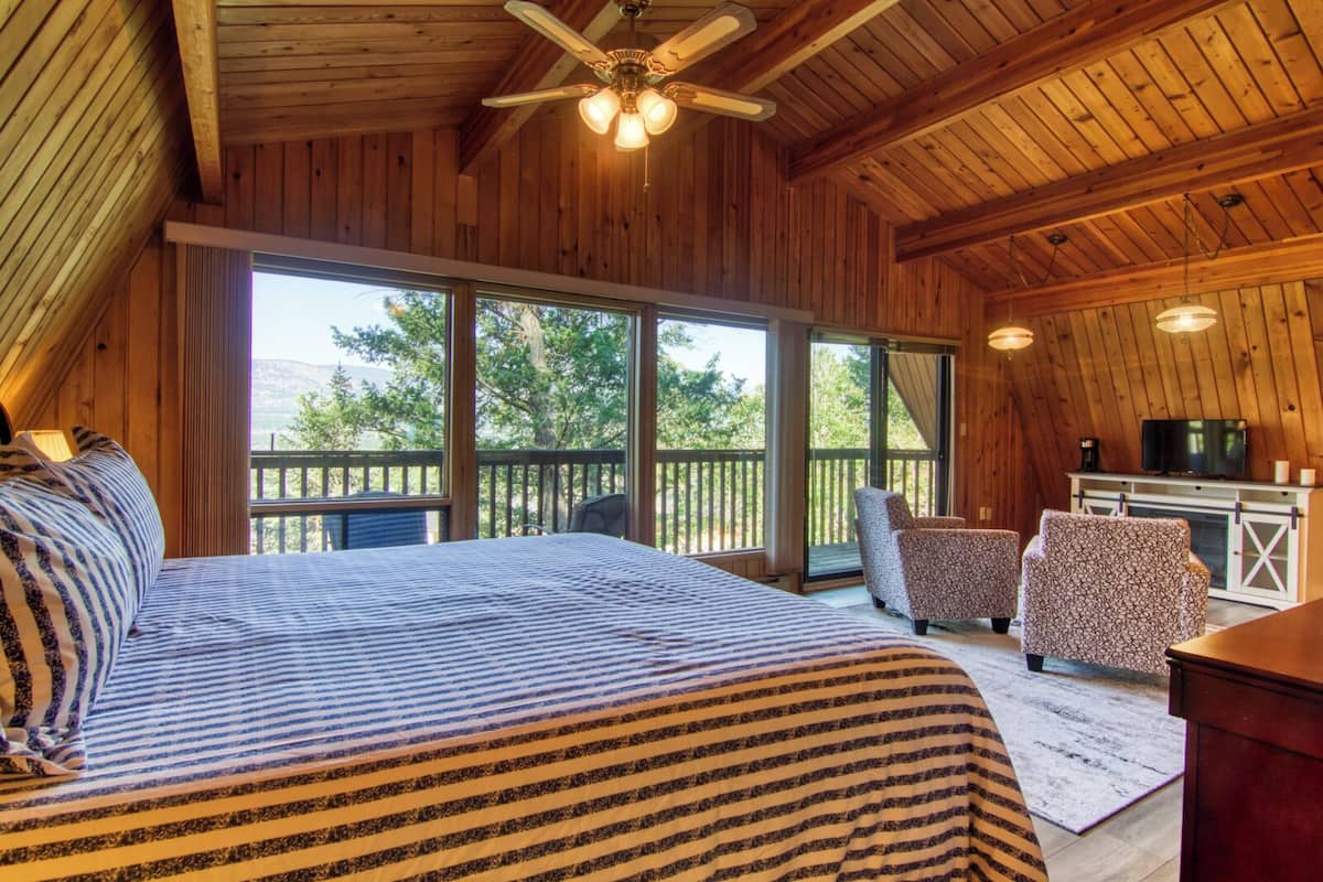 Un dormitorio acogedor con una cama grande, un ventilador de techo y vistas al exterior.