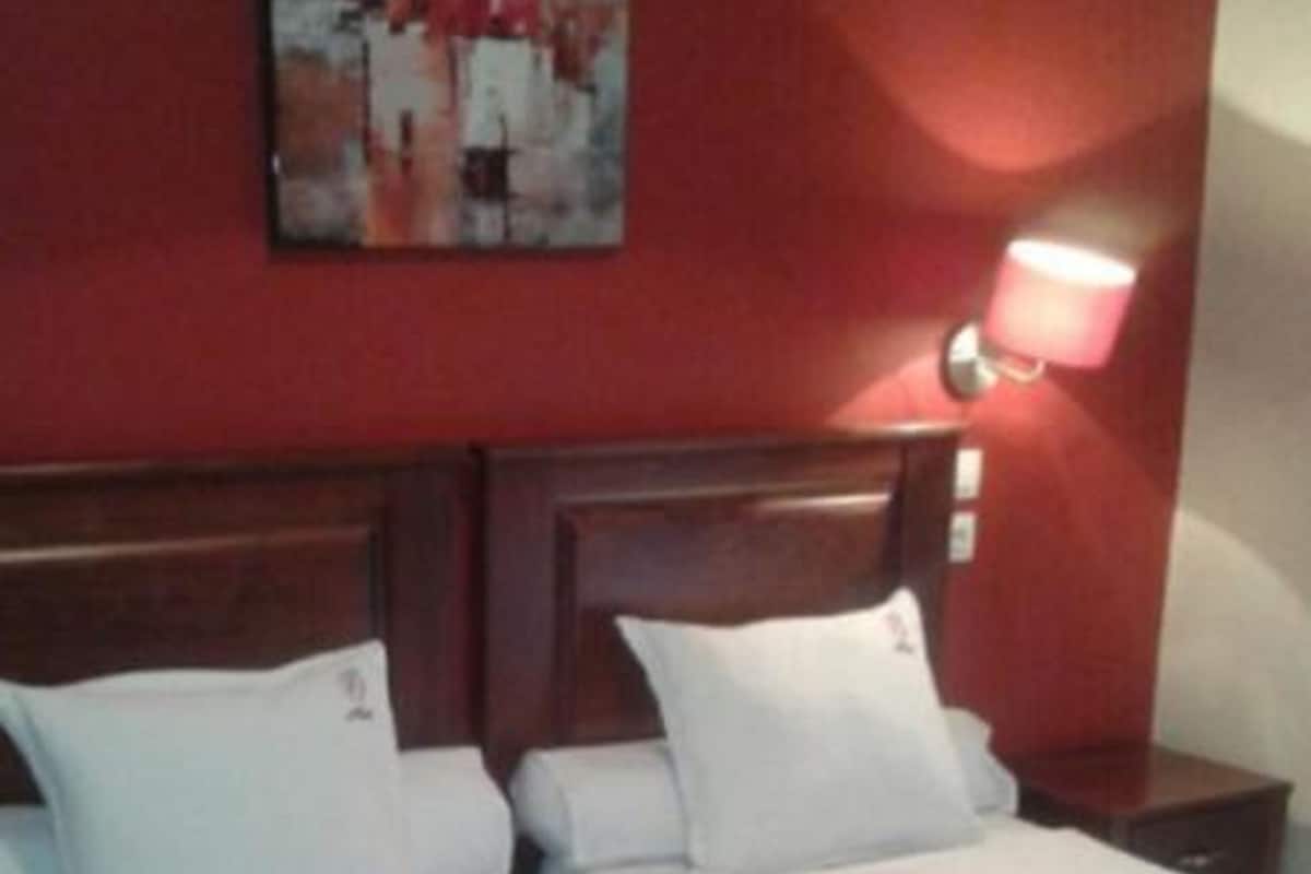 A double bed with floral bedding, a wooden headboard, and a nightstand with a lamp.