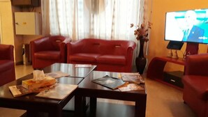 A living room with two red sofas, a glass coffee table, and a flat-screen TV. -  Hôtel Audin (Algiers)