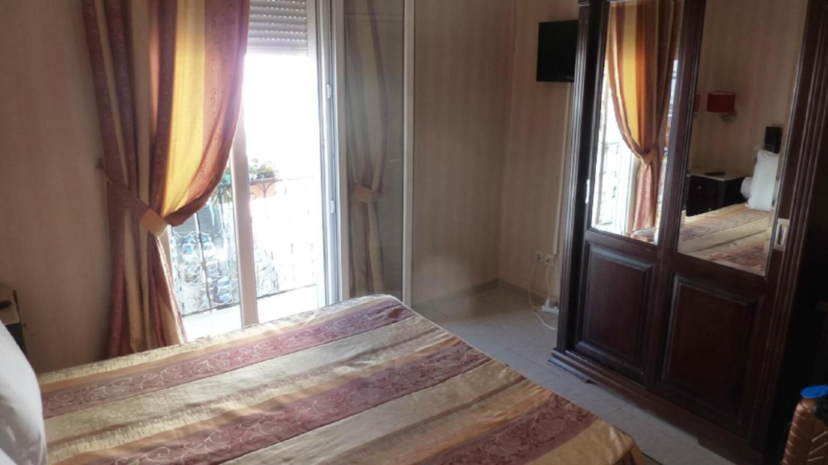 Ein Hotelzimmer mit einem Bett, einer Schiebetür und einem Fenster mit Vorhängen.
