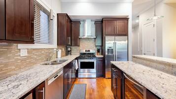 Una cocina moderna con armarios de madera oscura, encimeras de granito, electrodomésticos de acero inoxidable y vista al área de estar.