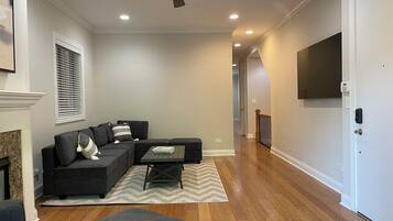 A modern living room with a sectional sofa, a coffee table, and a fireplace.