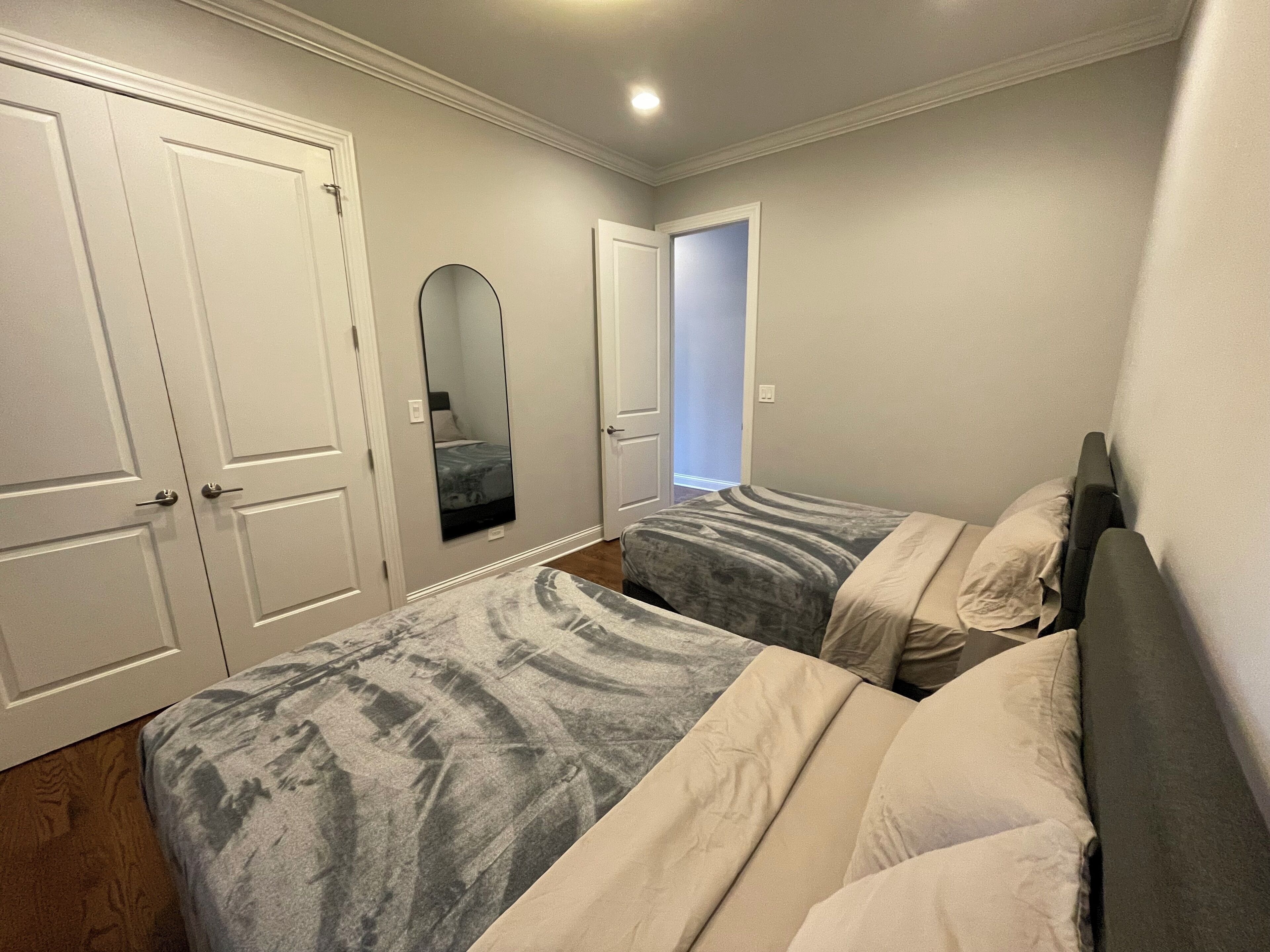 Een slaapkamer met twee bedden, een grote spiegel en witte deuren.