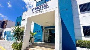 Fachada de hotel en azul y blanco, con una escalera que lleva a la entrada y un mural en la pared contigua.