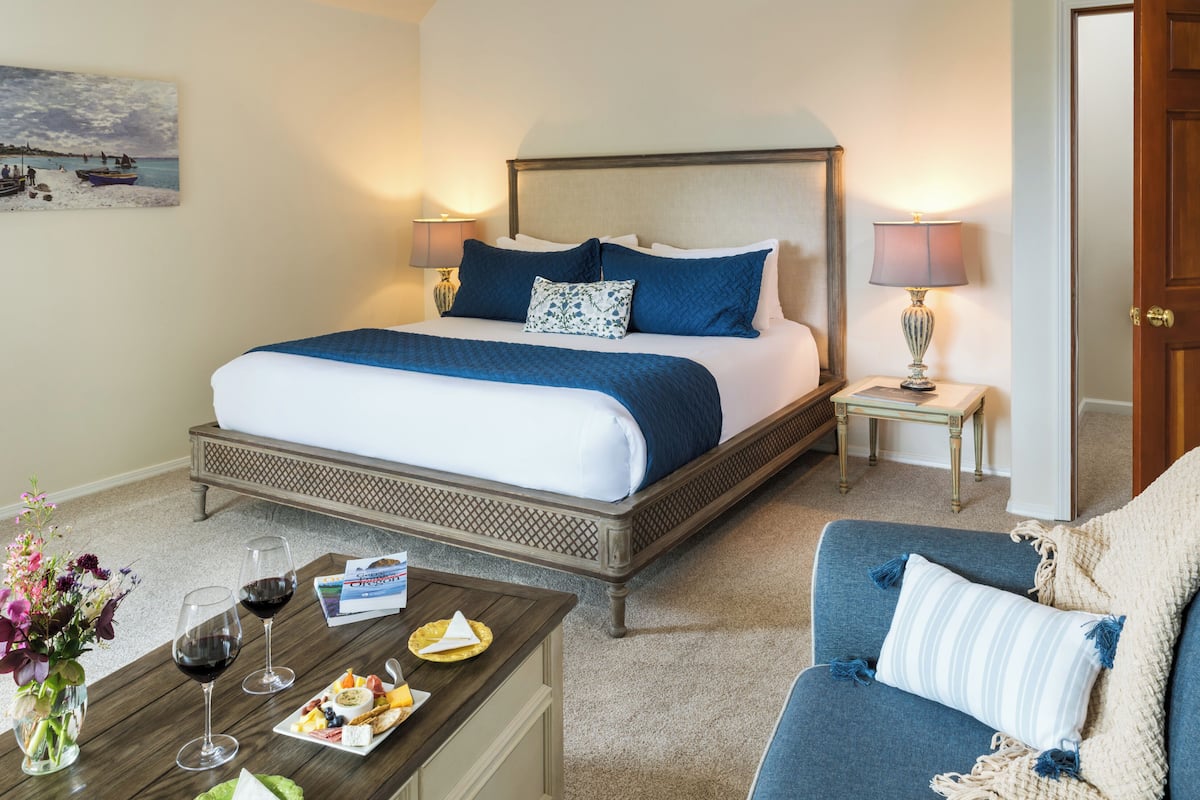 A hotel room with a bed, bedside tables, a coffee table with food and drinks, and a chair.