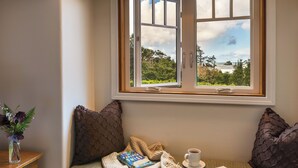 Un coin lecture confortable avec vue sur la mer, un livre, une tasse de café et une assiette de nourriture.