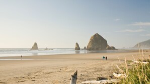 Une plage avec de grandes formations rocheuses et un ciel dégagé.