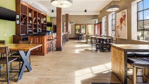 A spacious bar area with wooden flooring, bar stools, and a variety of bar equipment. - Jackson Park Inn, an Ascend Collection Hotel (Pulaski)