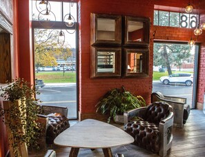 A cozy interior with a leather sofa, a wooden table, and a view of the street through large windows. - Jackson Park Inn, an Ascend Collection Hotel (Pulaski)