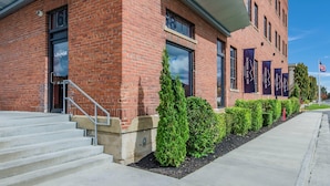 A brick building with a staircase leading to a door labeled "Lounge." - Jackson Park Inn, an Ascend Collection Hotel (Pulaski)