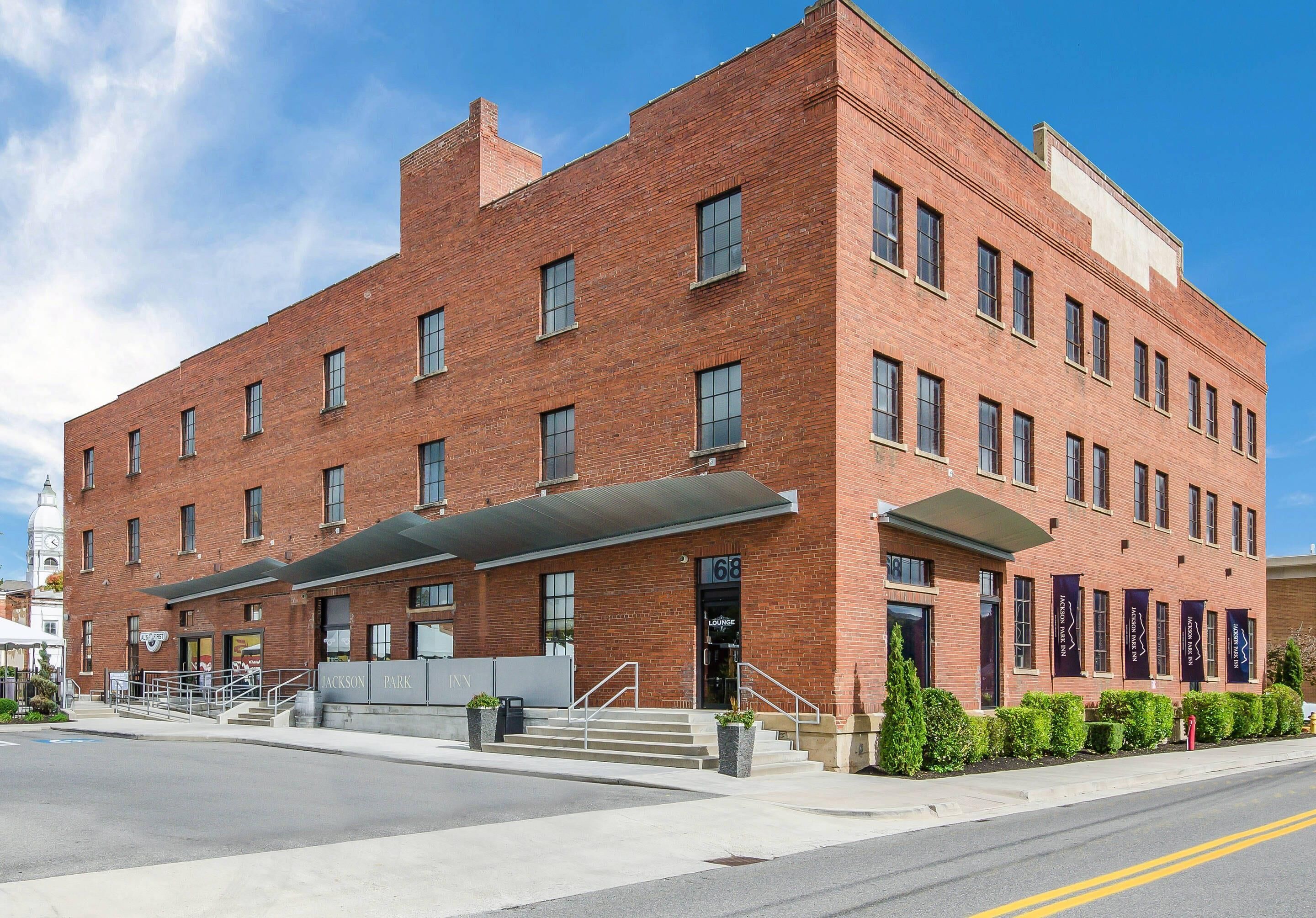 A red brick building with a covered entrance and a staircase leading to the door.