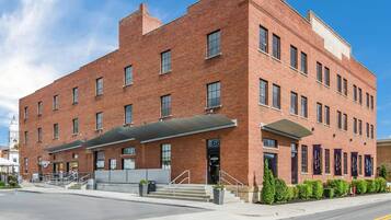 A red brick building with a covered entrance and a staircase leading to the door.