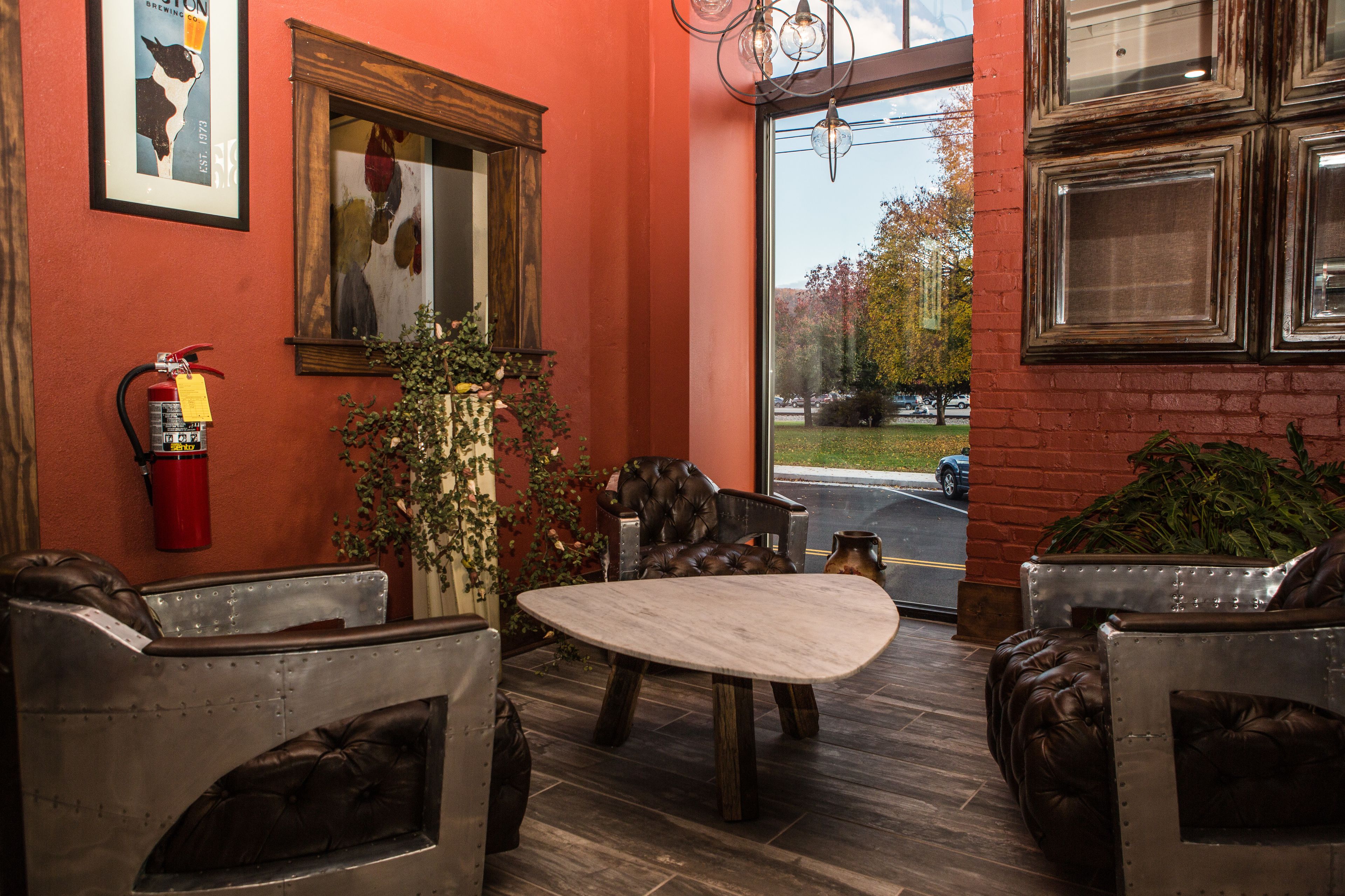 A cozy interior with leather chairs, a wooden table, and a fire extinguisher on the wall.