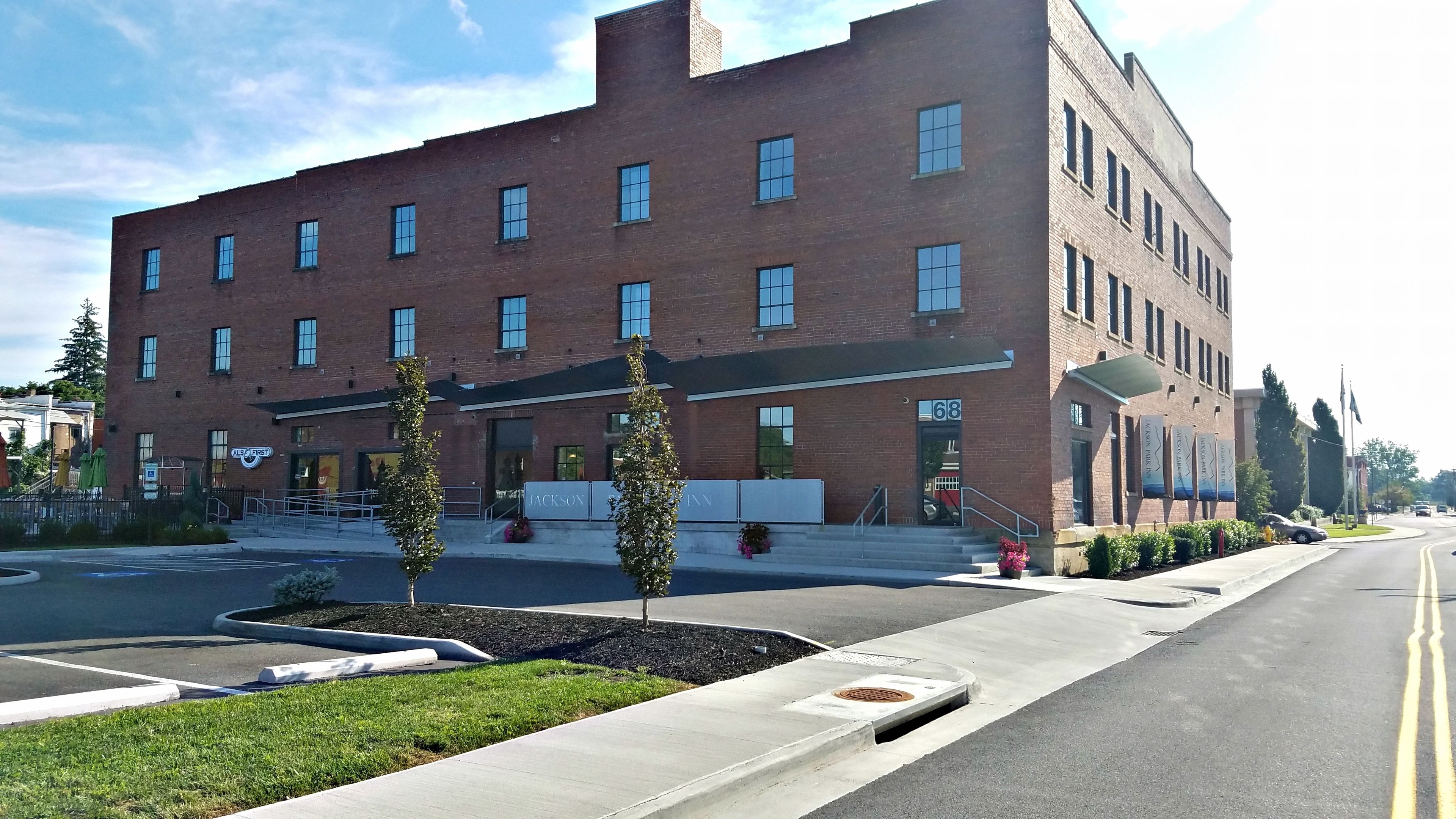A multi-story brick building with a flat roof, a large entrance with steps, and a sign for 'Jackson Inn'.
