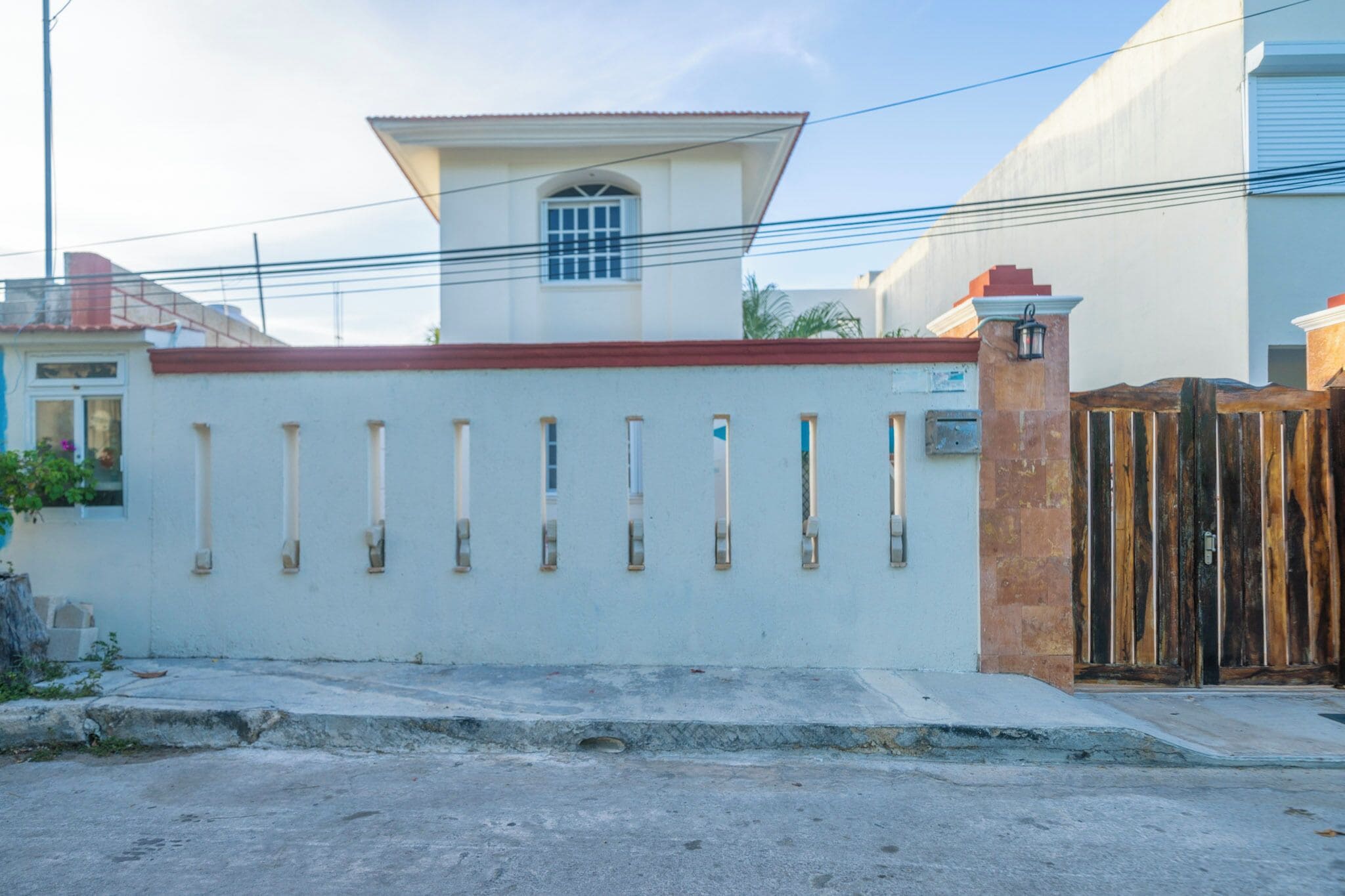 Un bâtiment blanc avec un toit rouge, une petite structure ressemblant à une tour et une clôture en bois avec des lattes verticales.