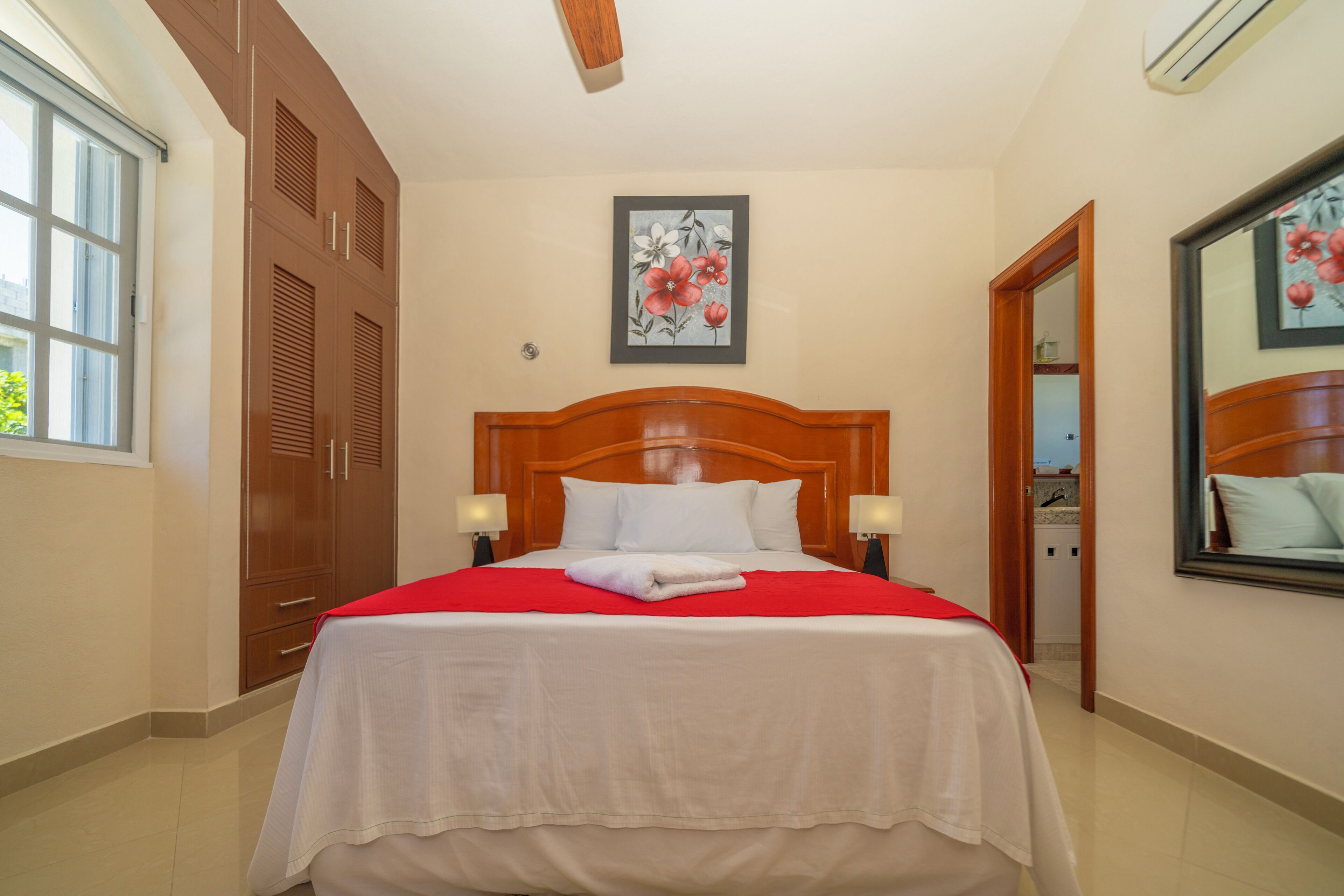A hotel room with a large bed, wooden wardrobe, and a painting on the wall.