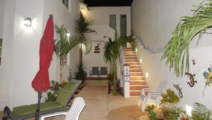 Un espacio al aire libre cubierto con escaleras, sillones y plantas en macetas.