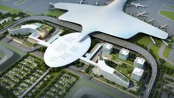 Una terminal de aeropuerto con un techo de diseño único en forma de estrella, múltiples terminales y un área de estacionamiento.