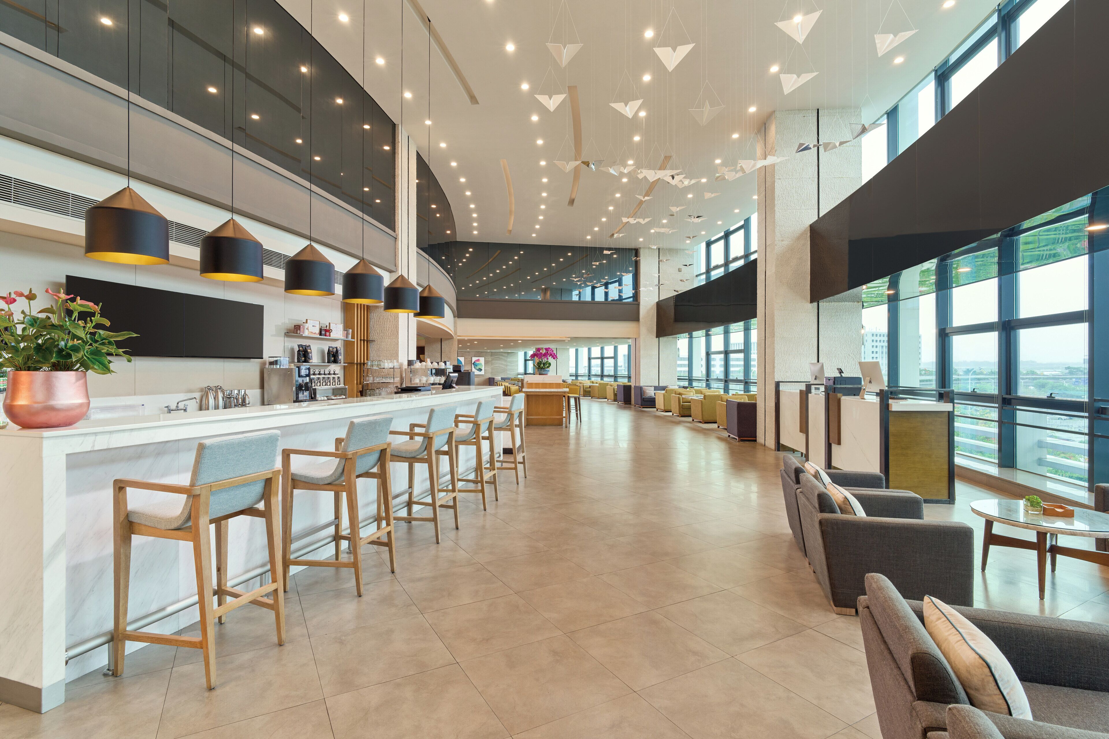 A modern bar area with a long counter, multiple bar stools, and a seating area with sofas and tables.