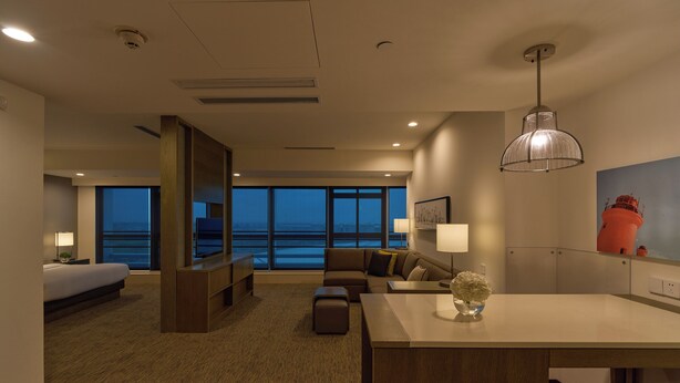 Un hotel moderno con un amplio ventanal que ofrece vista al mar, una zona de estar acogedora y un espacio para comer.