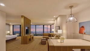 Una habitación de hotel moderna con una cama grande, un sofá, un comedor y vistas a la ciudad.