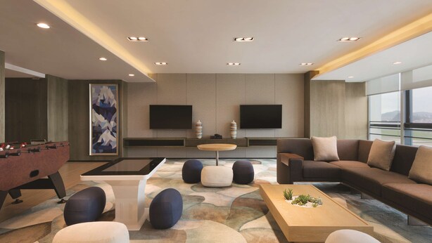 A modern living room with a foosball table, comfortable seating, a flat-screen TV, and a large window offering a view. - Hyatt House Shenzhen Airport (Shenzhen)