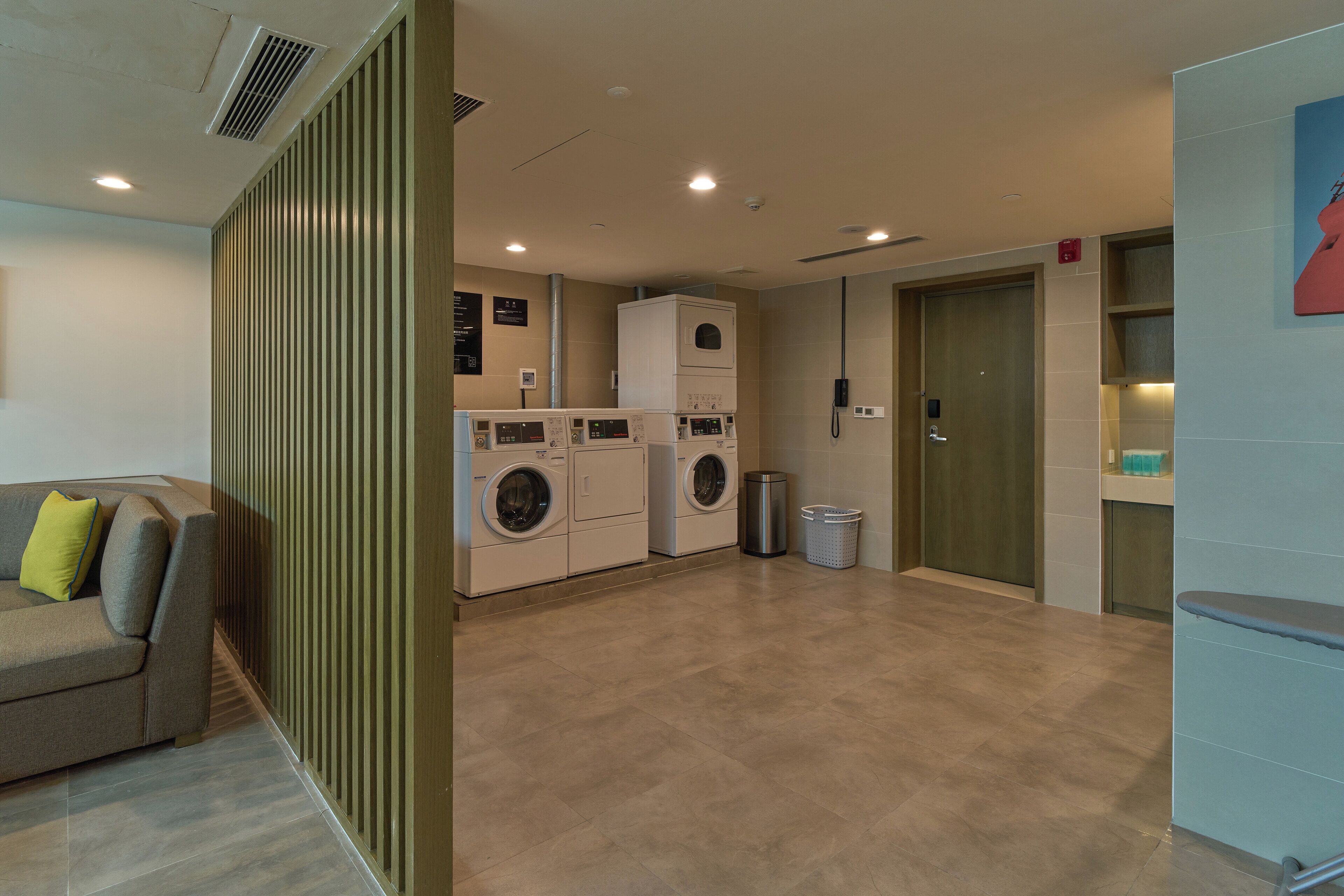 Une chambre d’hôtel moderne équipée d’un canapé, d’un lave-linge et d’une poubelle.