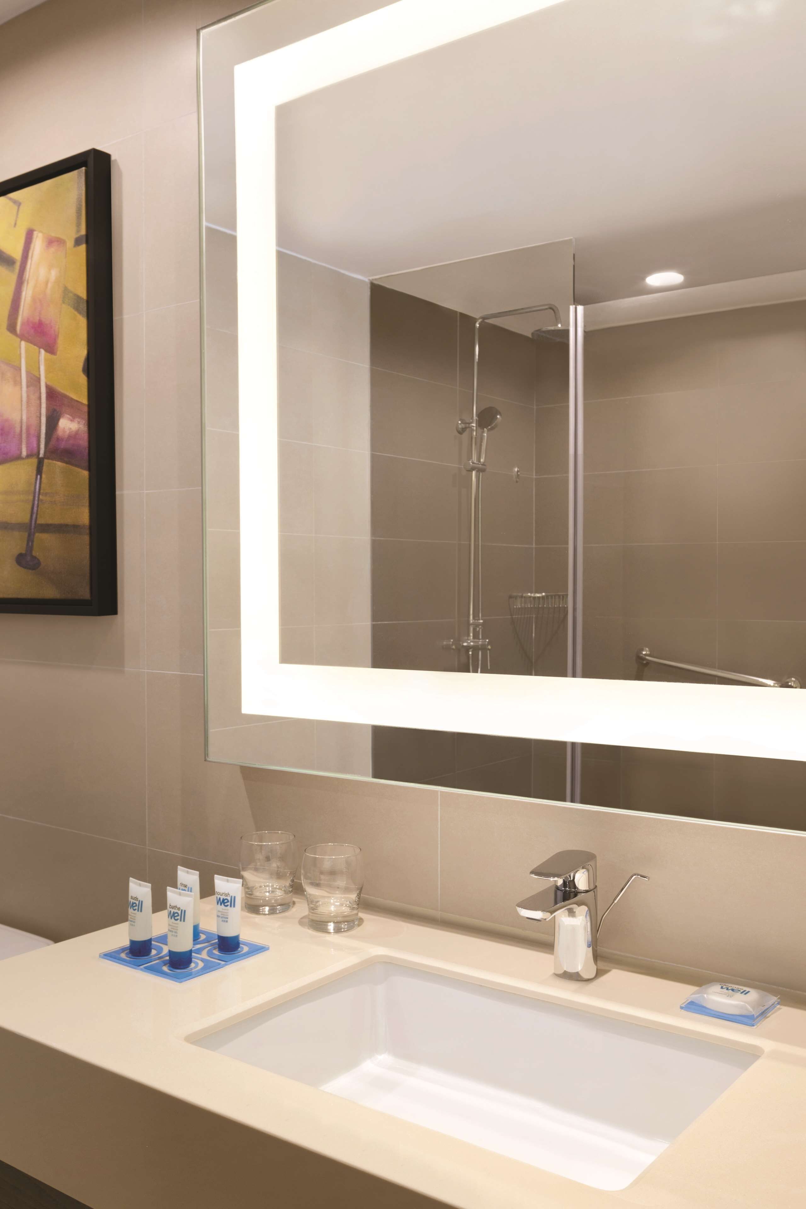 A modern bathroom with a large mirror, a sink, and a shower.