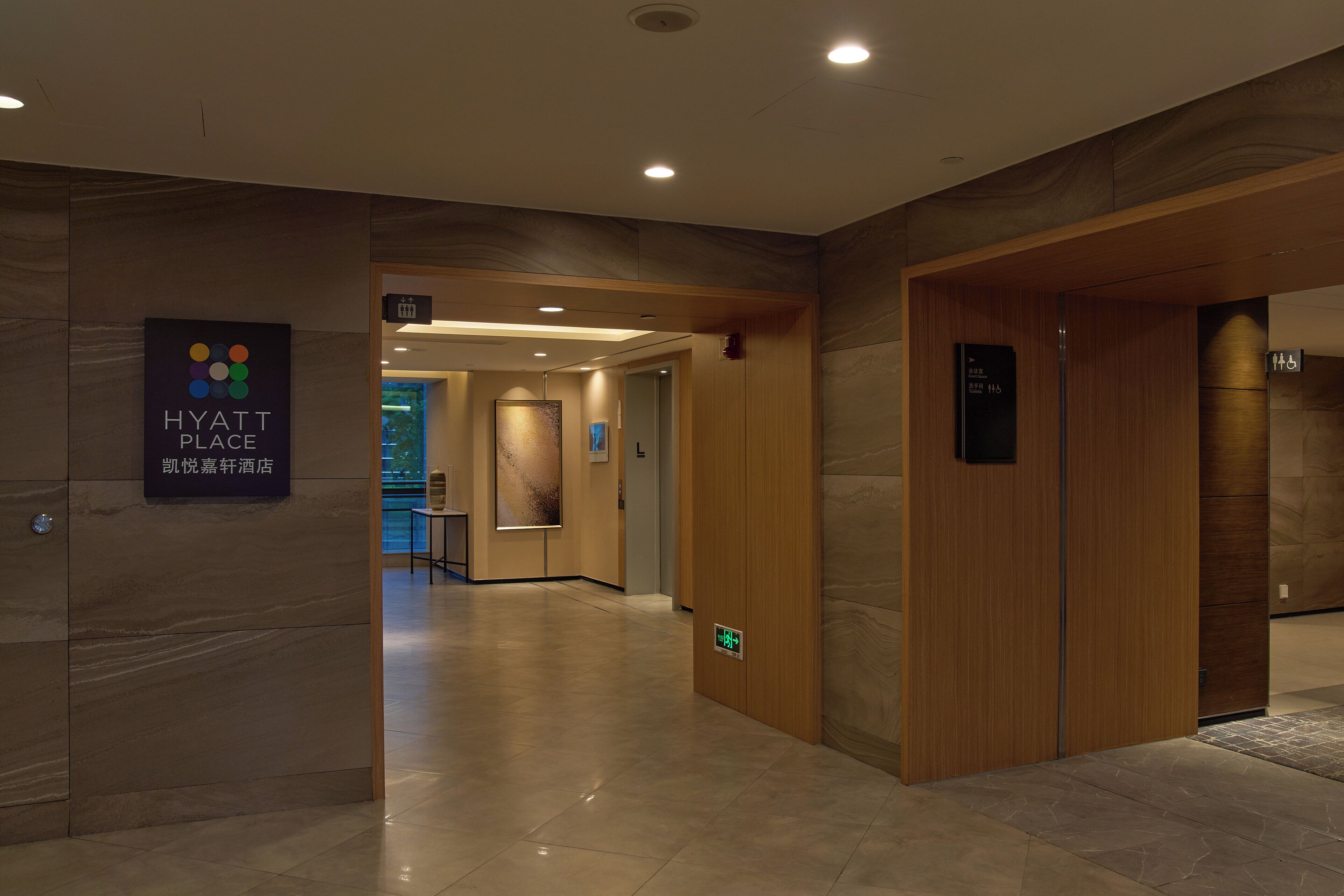 Eine moderne Hotelhalle mit Marmorboden, Holztüren und einem Schild für Hyatt Place.