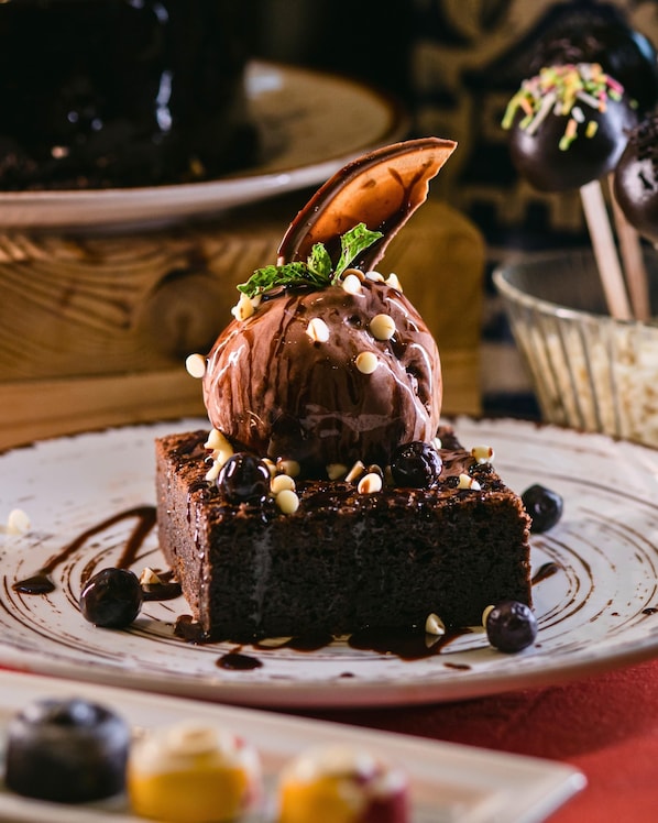Un postre con pastel de chocolate, helado y adornos en un plato.