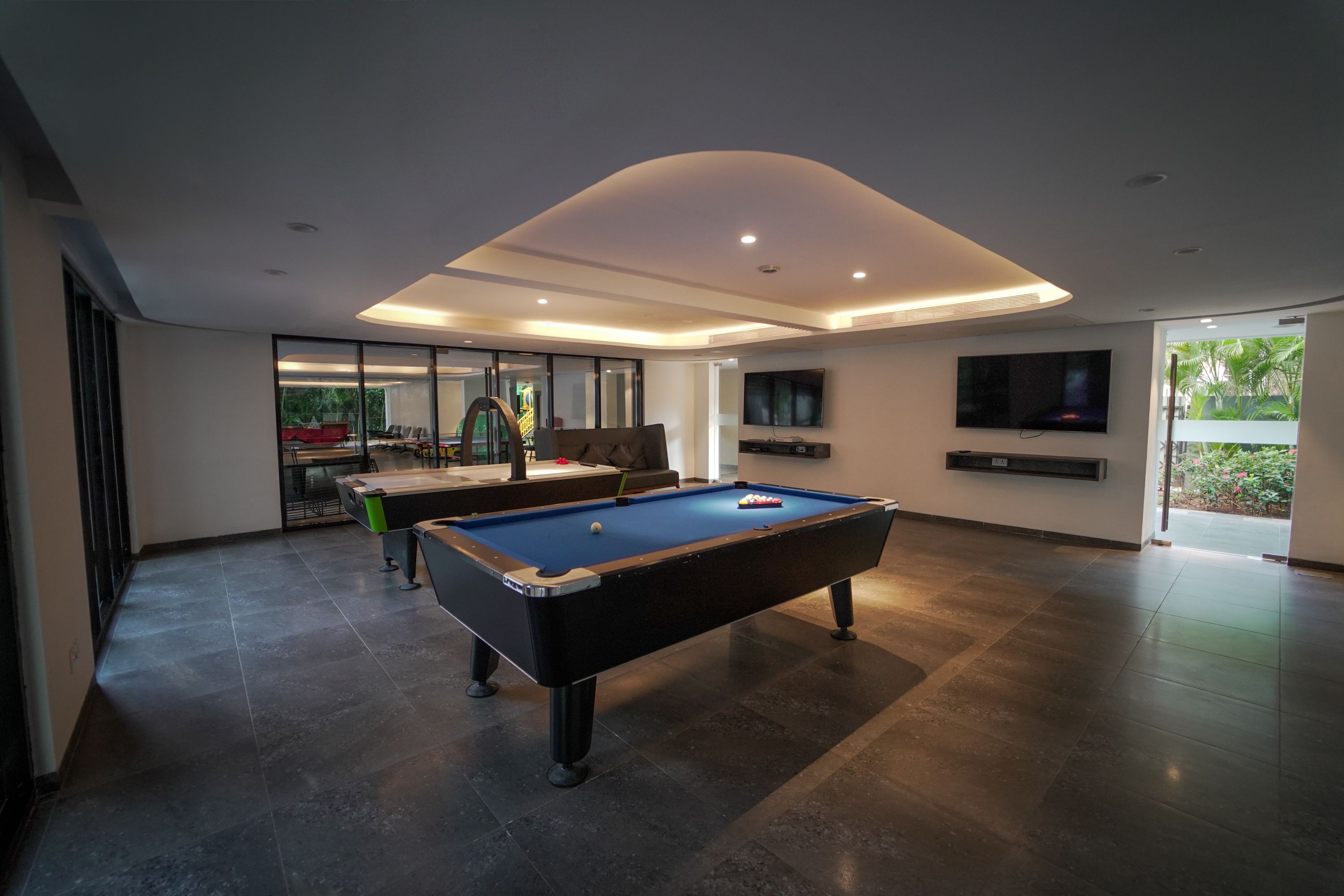 A modern living room with a pool table, a sofa, and a television.
