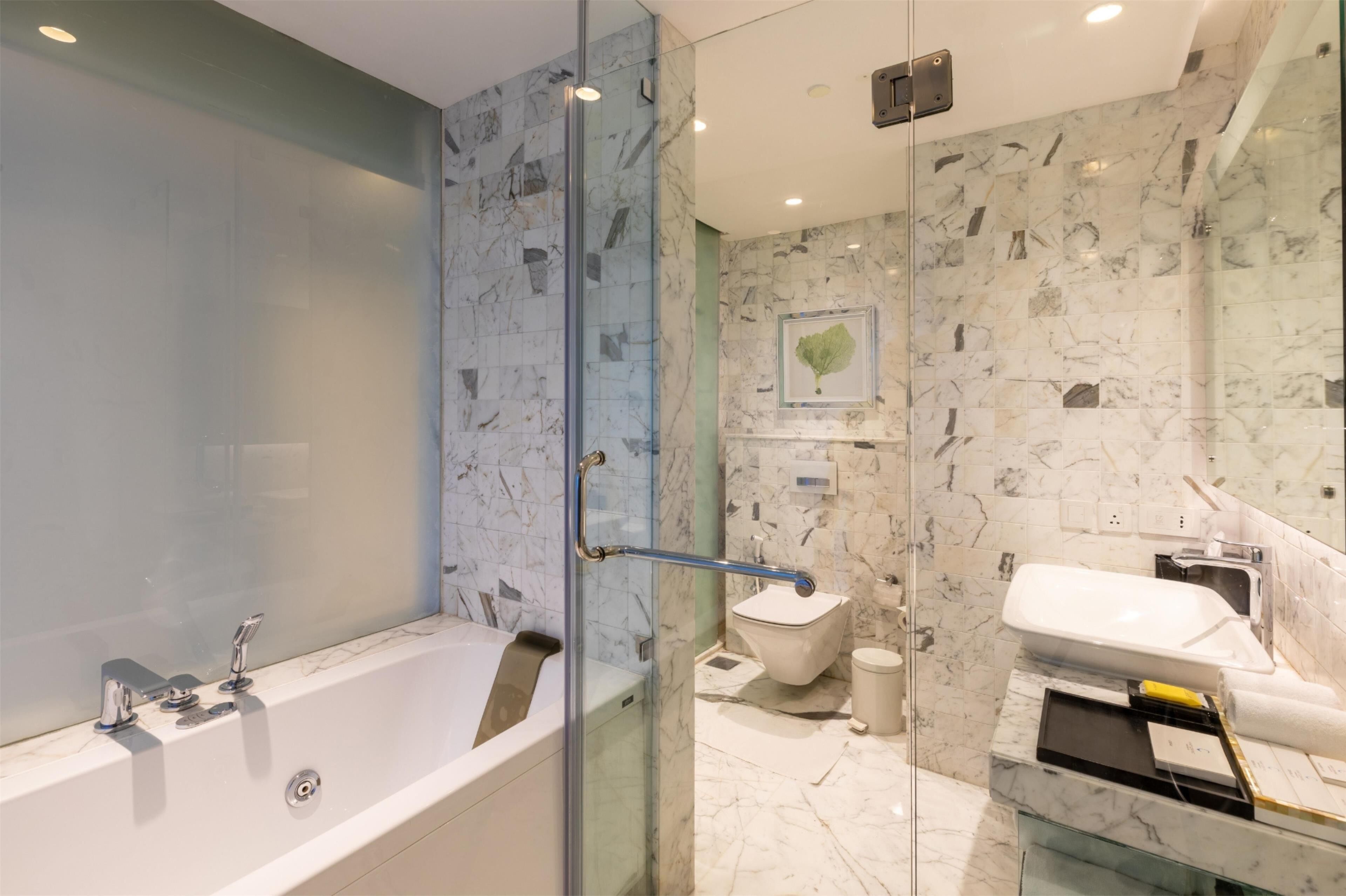 A modern bathroom with a glass-enclosed shower, a white bathtub, and a toilet.