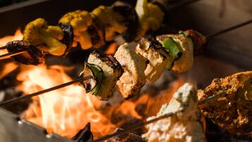 Brochetas de verduras a la parrilla y carne sobre fuego abierto.