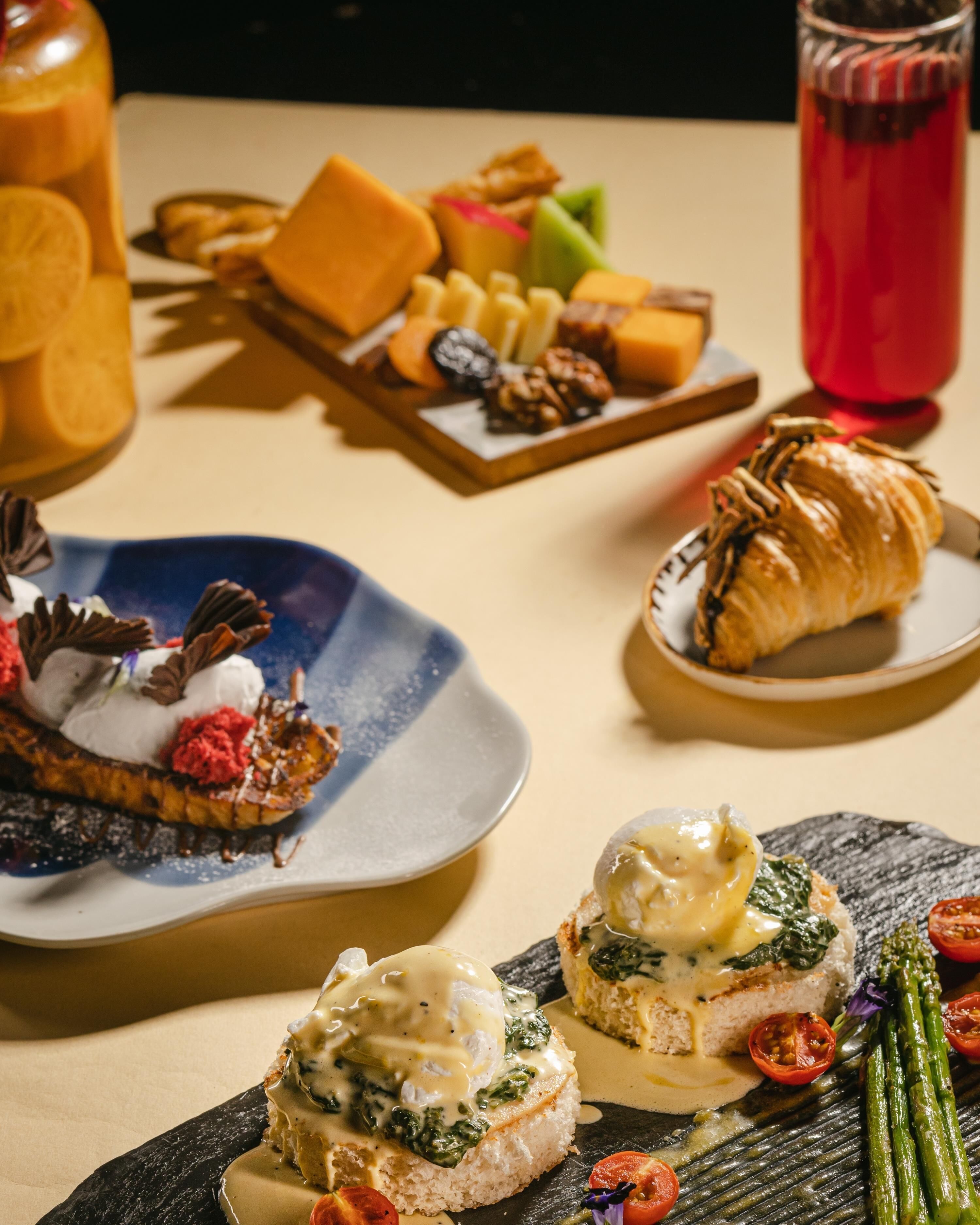 Variedad de platos, incluyendo un postre con crema batida y chocolate, un croissant y un plato con espinacas y huevos.