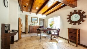 Una habitación amplia con techo de madera, una mesa de comedor con sillas, un espejo grande y un armario de madera.