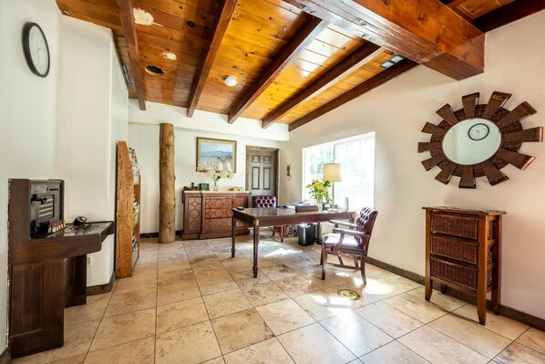 Una habitación amplia con techo de madera, una mesa de comedor con sillas, un espejo grande y un armario de madera.