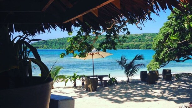 A beachside seating area with a thatched roof, potted plants, and a view of the ocean. - Two Canoes Island Getaway (Aore Island)