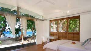 A bedroom with a bed, desk, and a view of the beach and ocean. - Two Canoes Island Getaway (Aore Island)