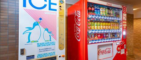 Una máquina expendedora con el logotipo de Coca-Cola y otra máquina con un diseño azul y blanco que dice 'ICE'.