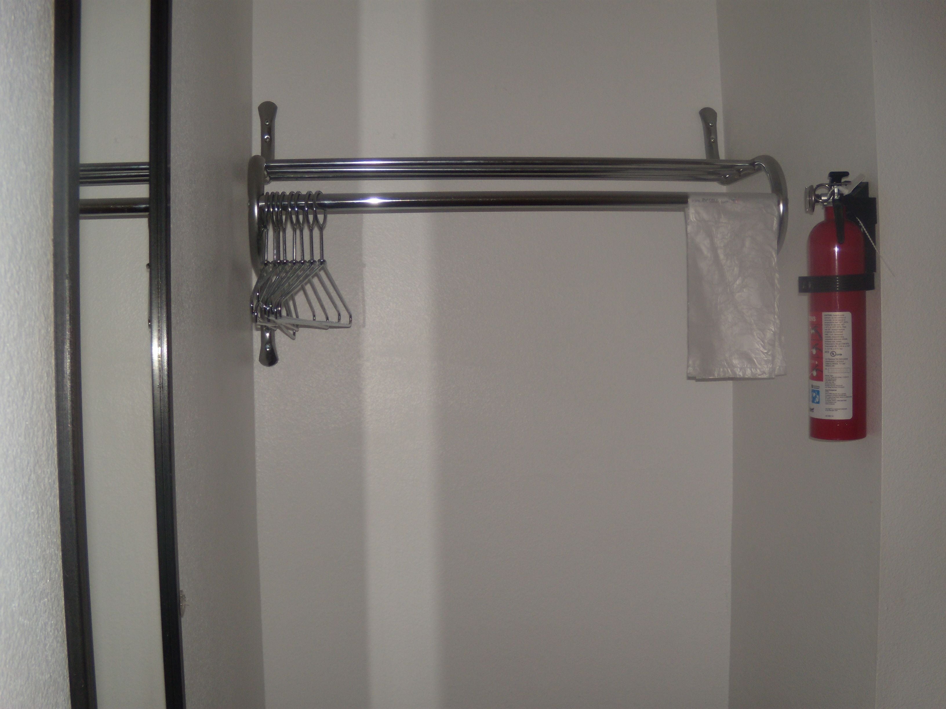 A bathroom with a towel rack, a metal basket, and a fire extinguisher.