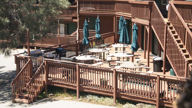 Una terraza de madera con varios niveles, mobiliario exterior y una piscina.