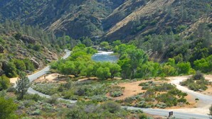 Un camino serpenteante a través de un cañón, con un río a lo lejos.