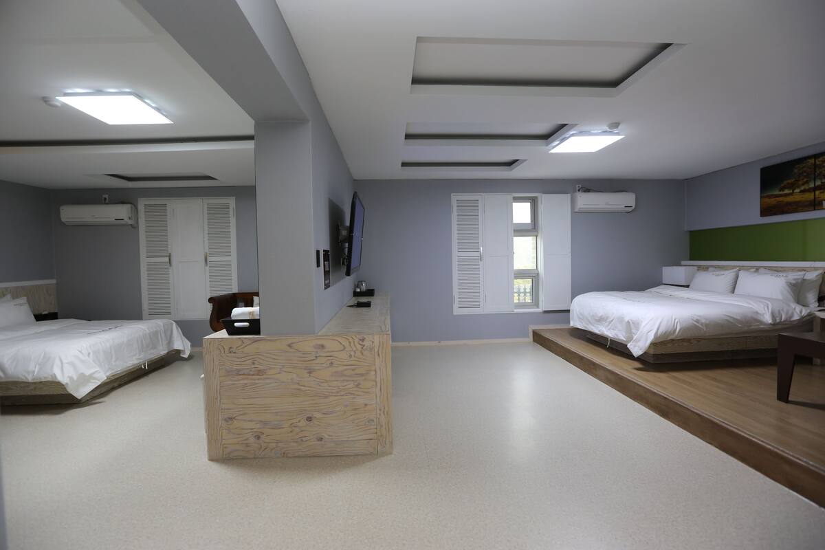 Ein Hotelzimmer mit zwei Betten, einem Holztisch und einem großen Fenster.