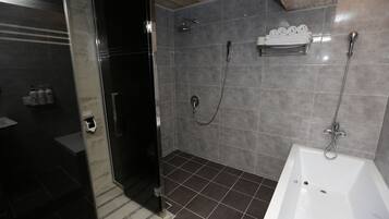 A modern bathroom with a glass shower enclosure, a white bathtub, and a towel rack with neatly folded towels.