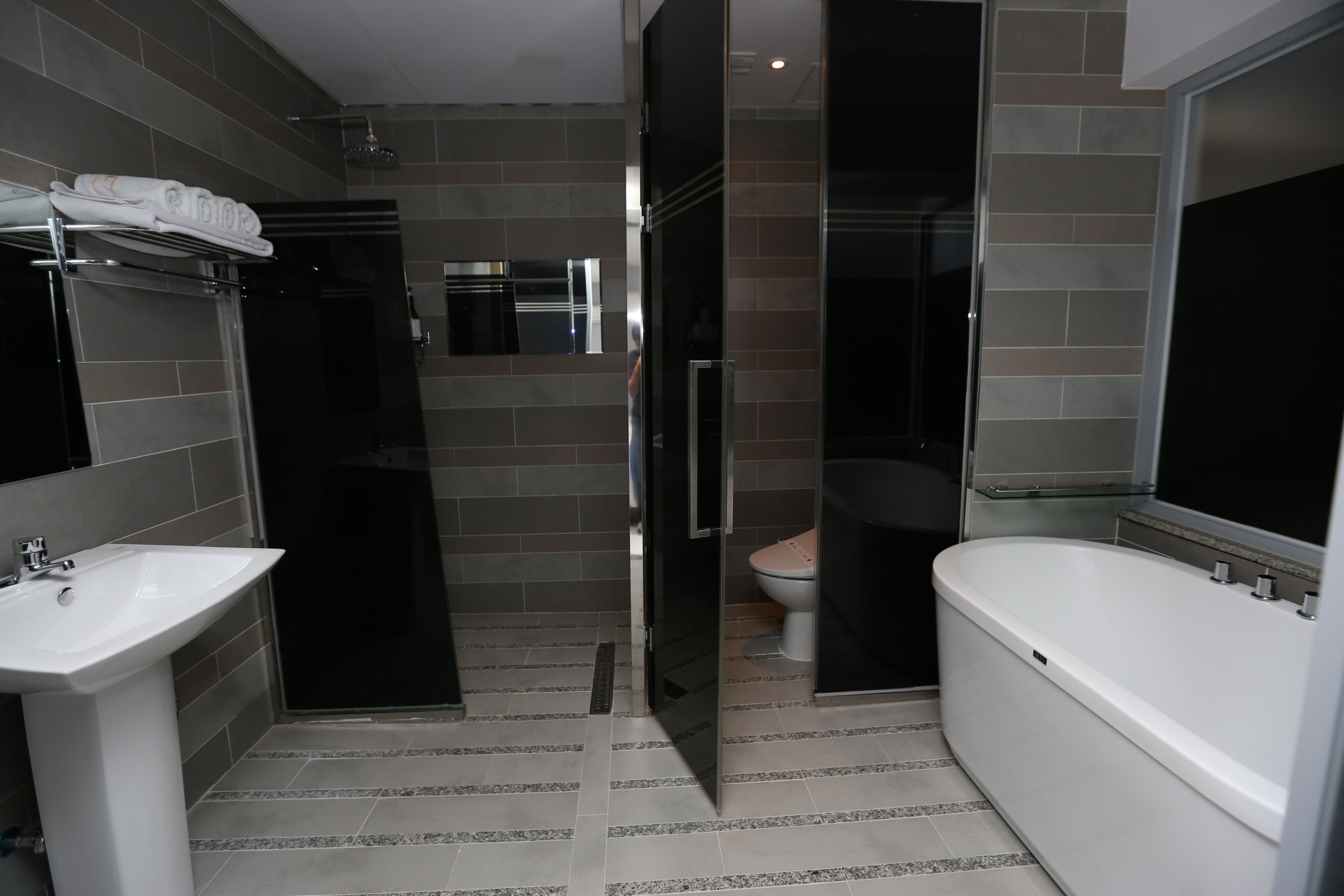 A modern bathroom with a white sink, a bathtub, and a toilet.