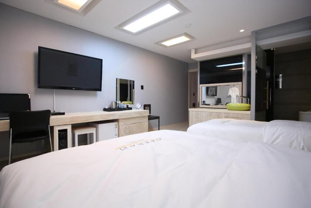 Une chambre d’hôtel avec deux lits, un bureau, un téléviseur à écran plat et un miroir.